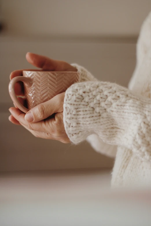 woman's hands holding cup that has a triangle shape on it