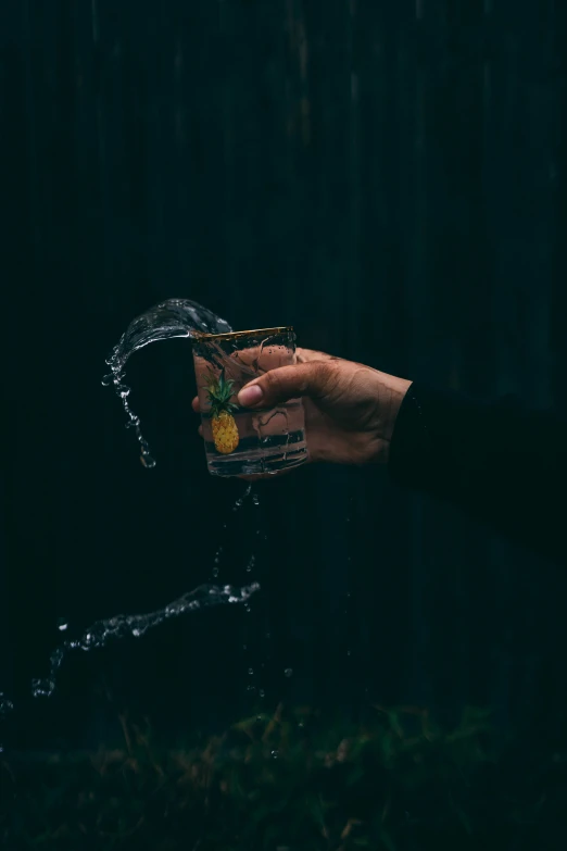 an outstretched hand reaching into a glass with a cocktail