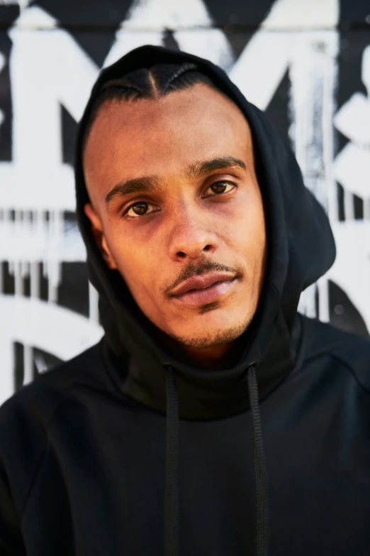 a young man wearing a hoodie and looking at the camera