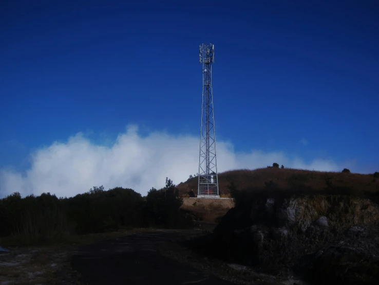 a large tower on a hillside with clouds around it