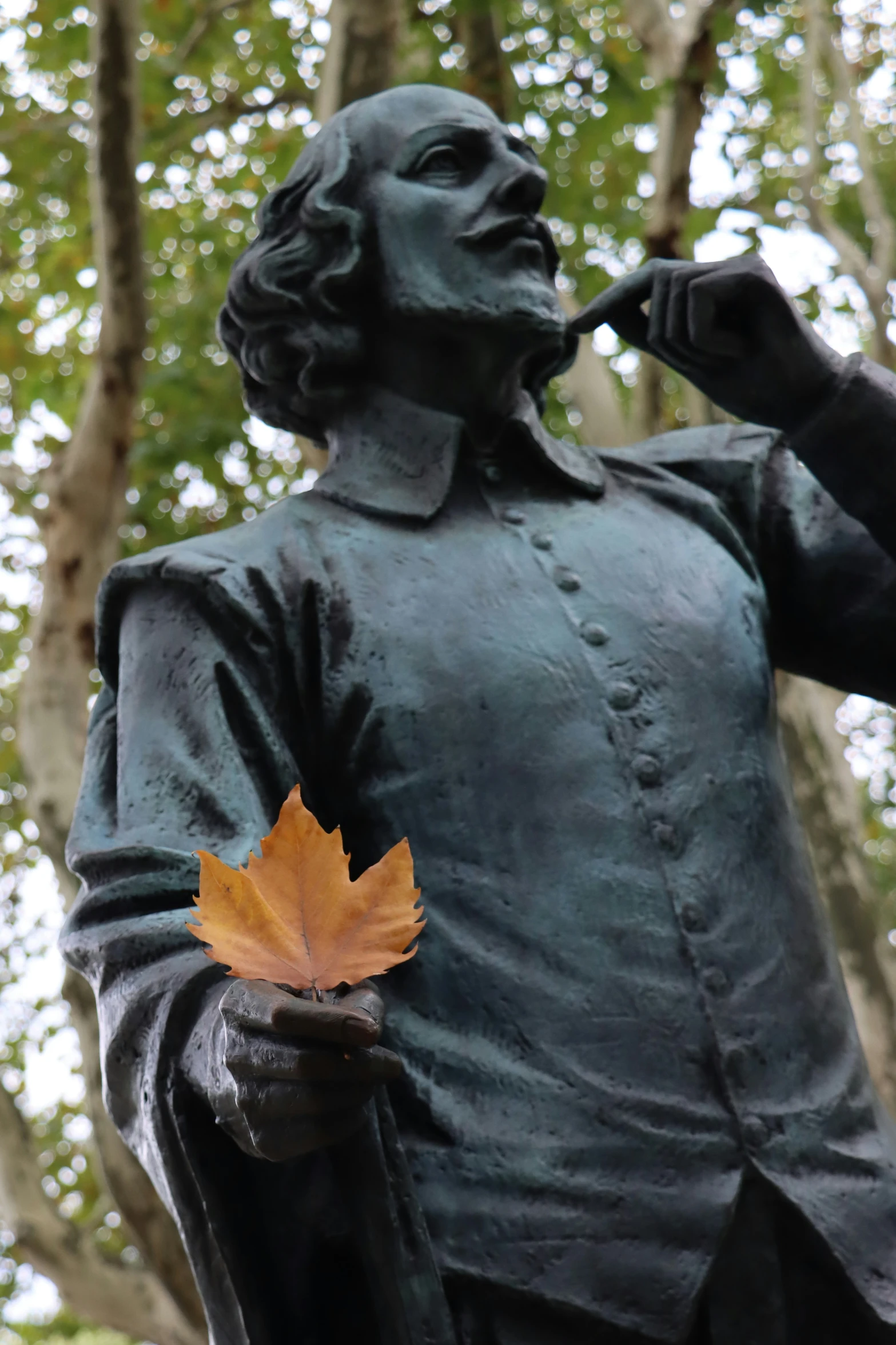 a close up of a statue of a person with a leaf in his hand