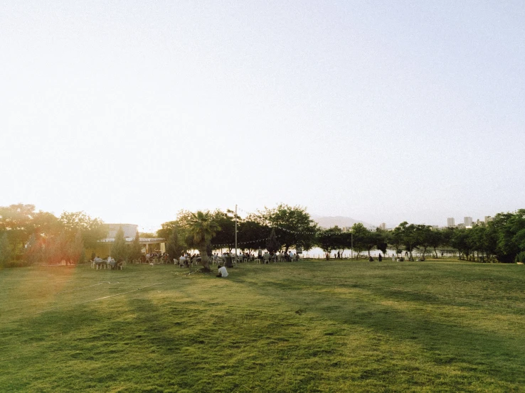 people are walking around the park during sunset