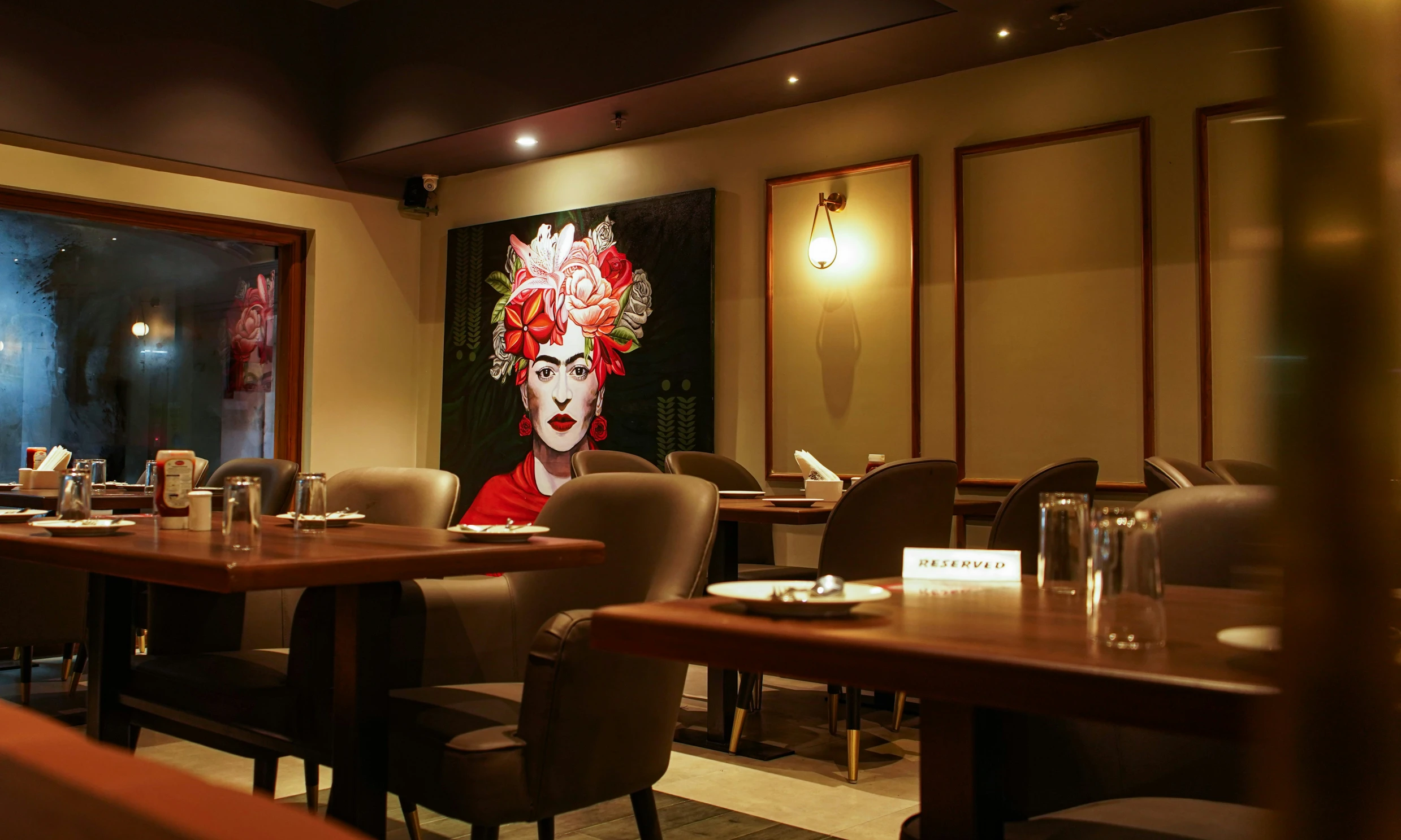 an empty restaurant with a painting of a woman behind it