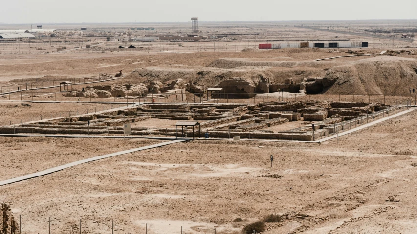 a field of dirt with small buildings in the middle