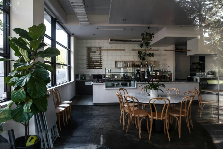 a dining room with a kitchen in the back and a table surrounded by chairs