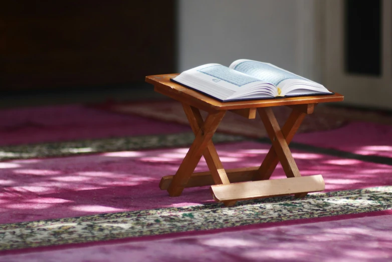 open bible on folding wood stand on purple rug