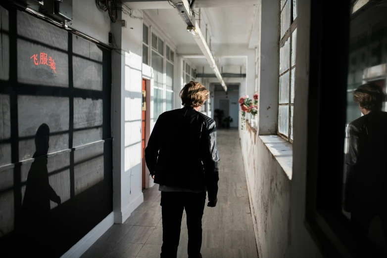 a man walking down an empty corridor next to another building