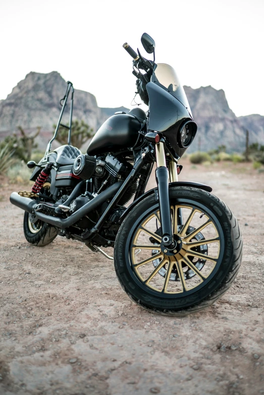 a motorcycle with golden tires sitting in the dirt