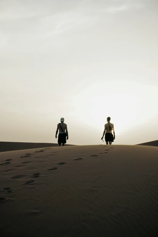 two people are walking across the desert