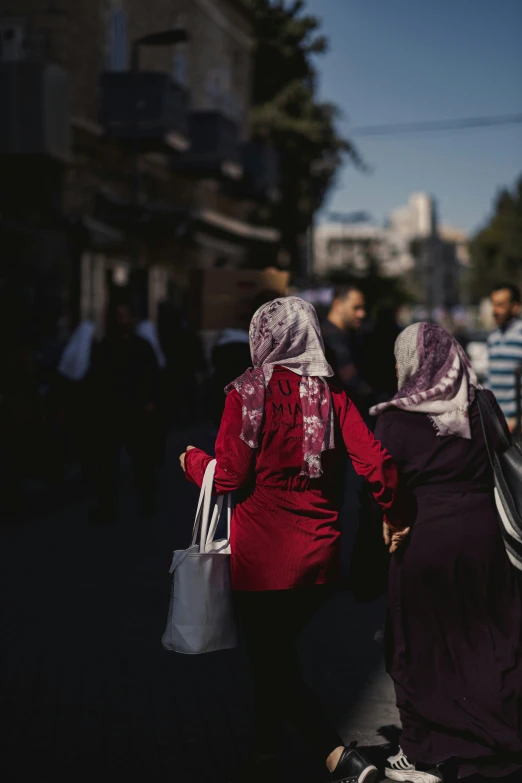 two women are walking down the street holding shopping bags