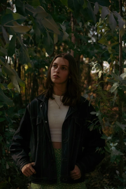 a woman is standing in a forest with trees