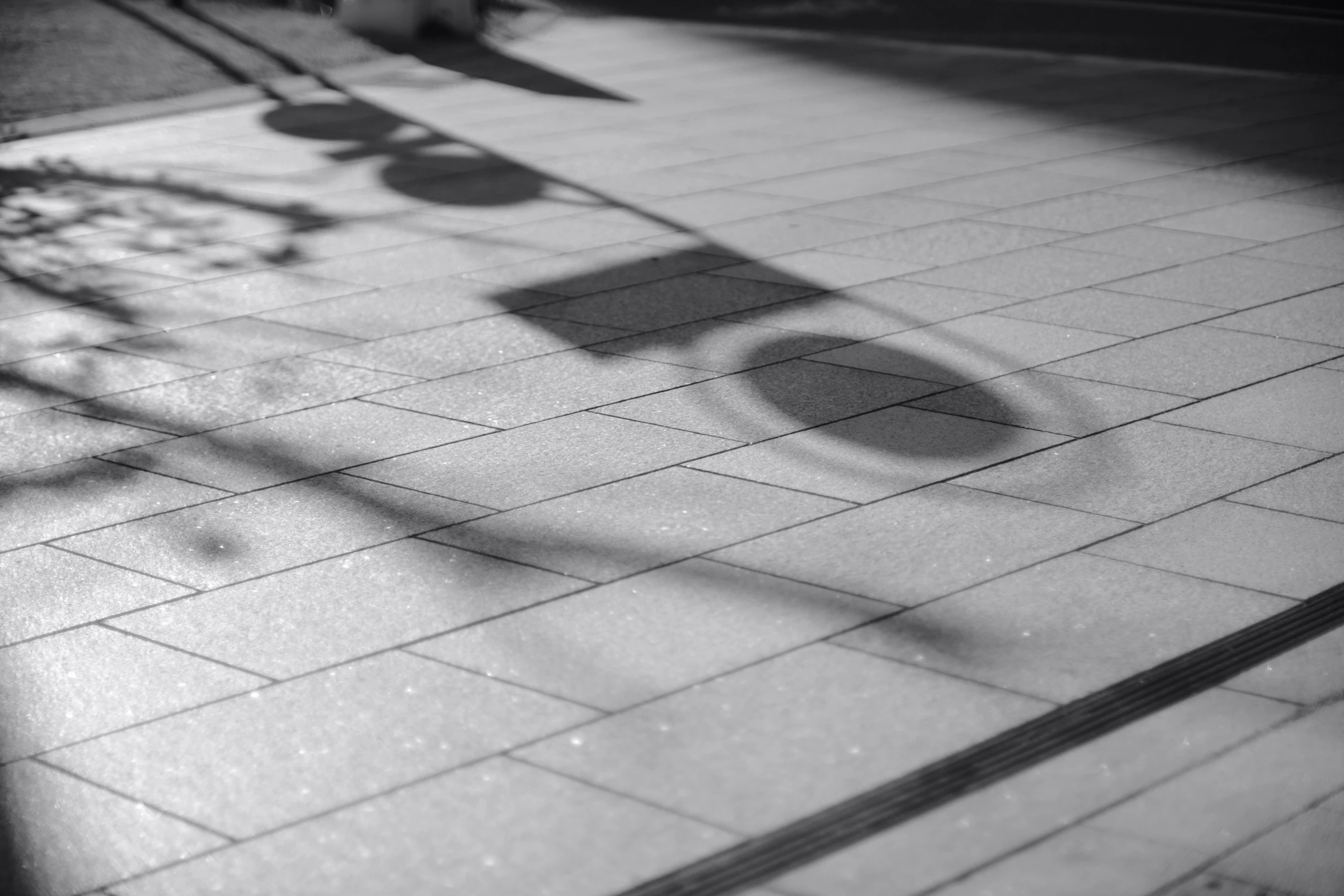 shadow of street light casting a long shadow on a tile walkway