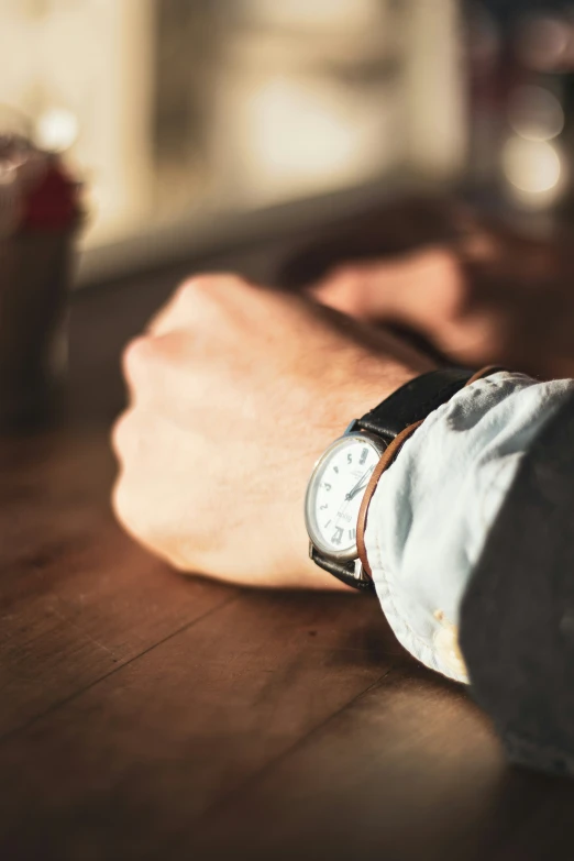 someone's wrist and watch on a table