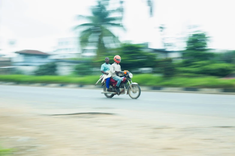 three people on a motorcycle on a rural road