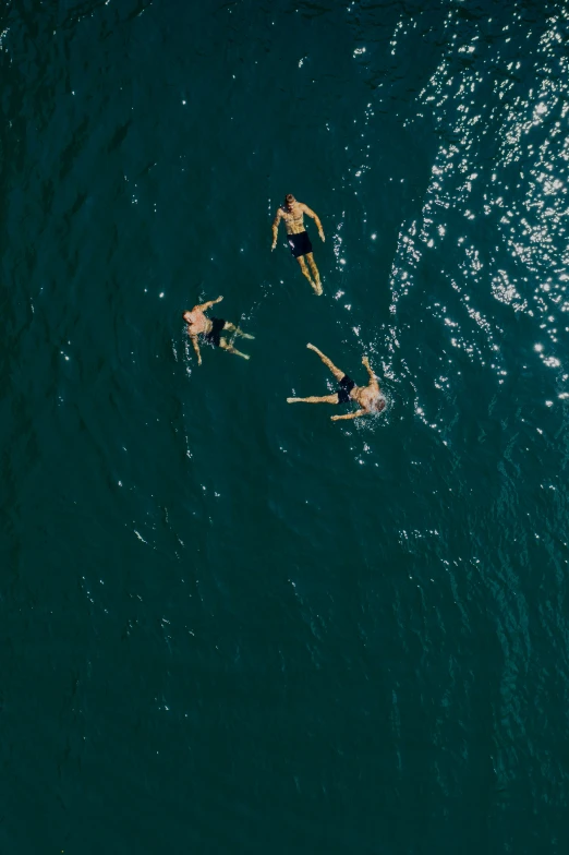 three people swimming in a large body of water