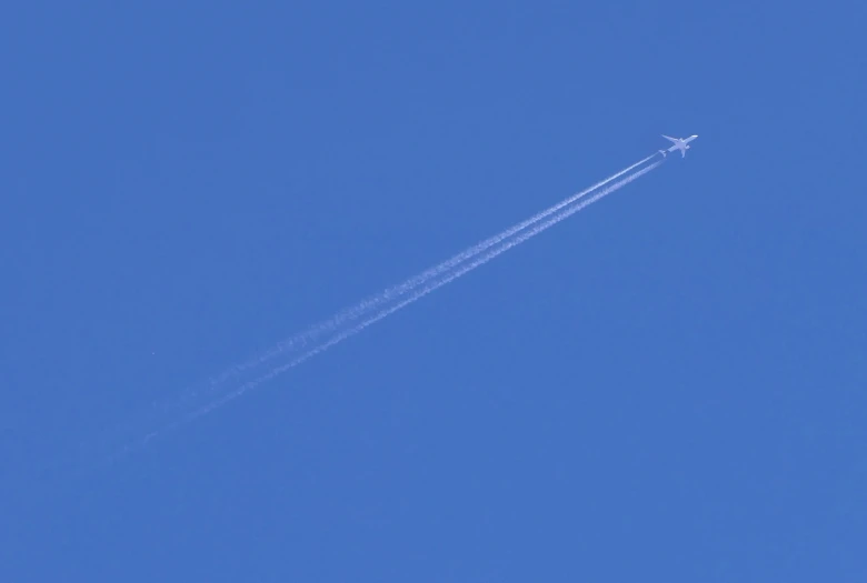 the airplane is leaving a trail in the clear blue sky