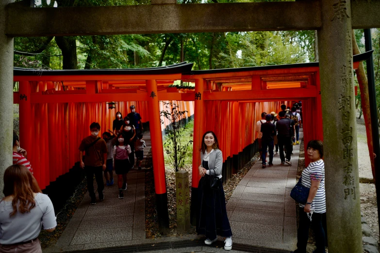 a woman poses in front of an orange gate