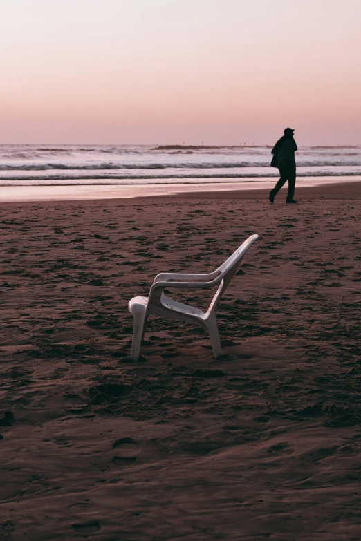 a bench on a beach with the sun setting in the background