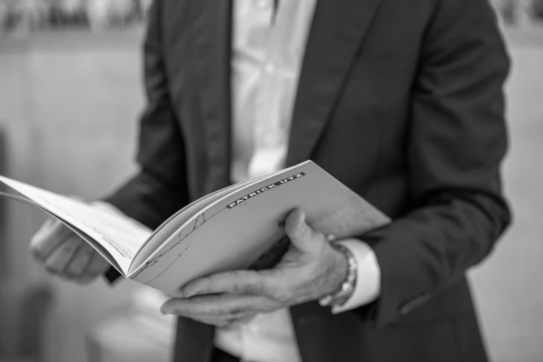 a man in suit and tie holding open book