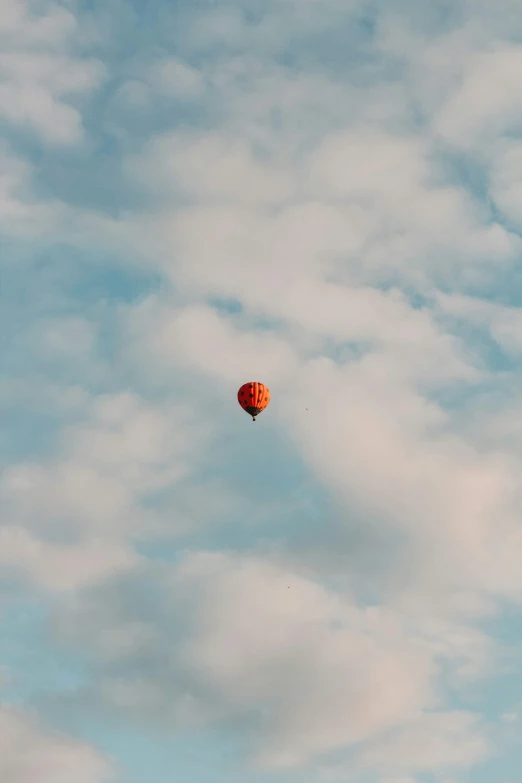 an orange balloon is in the air above clouds