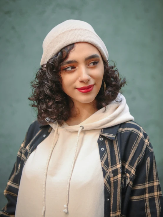 a young woman with curly hair wearing a white hat