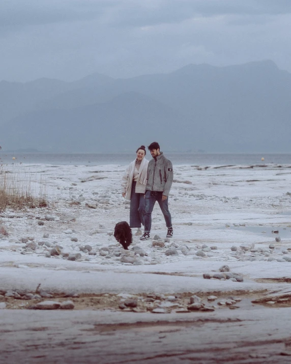 two people in the snow with a dog in their lap