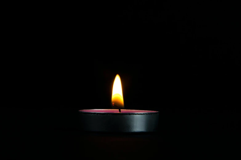 a candle that is lit up with dark background