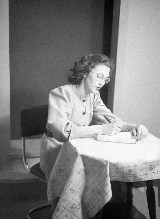 a woman sitting at a table with a book in her hand