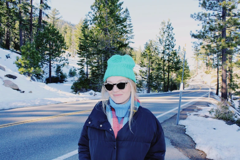 a woman in sunglasses standing on the side of a road