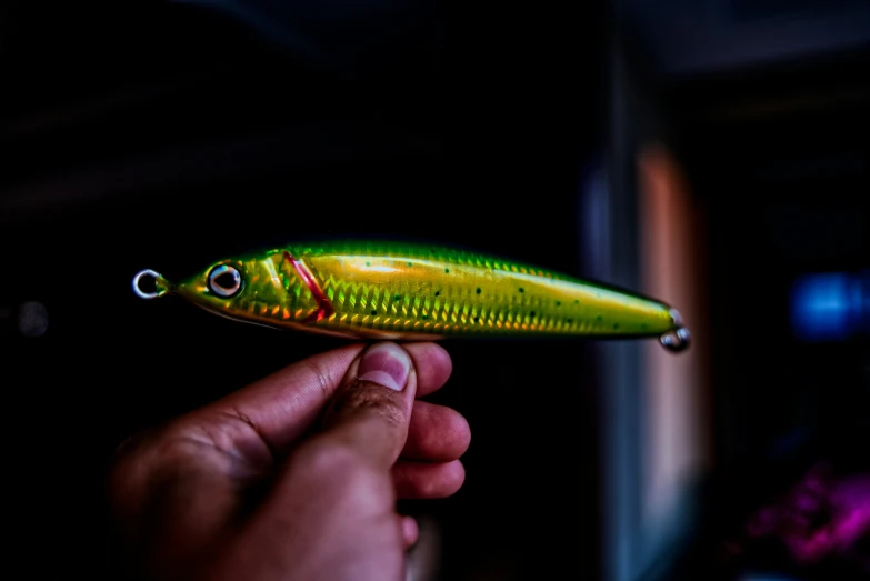 a man holding a yellow plastic fishing lure in the dark