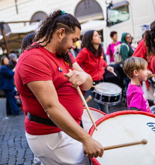 the man is drumming with an instrument to demonstrate his ability