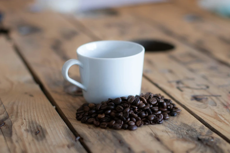 coffee beans are next to a small white cup