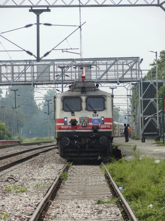 a train going down the tracks with two people around