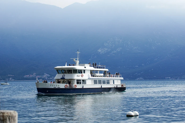 a ferry boat sailing on the water near mountains