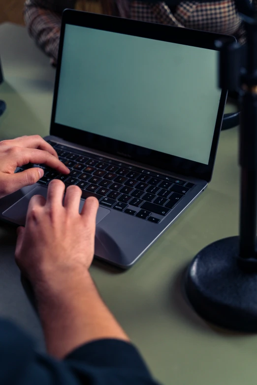 man on laptop computer at table with microphone in dark area