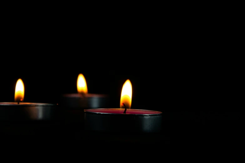 candles lit against a black background in the dark