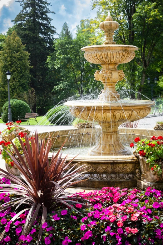 a large fountain surrounded by a garden with lots of flowers