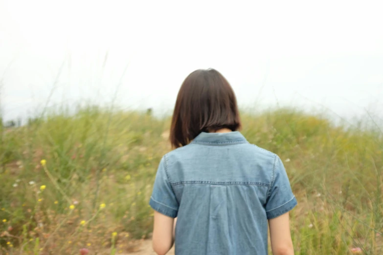 a person with long hair walking through grass