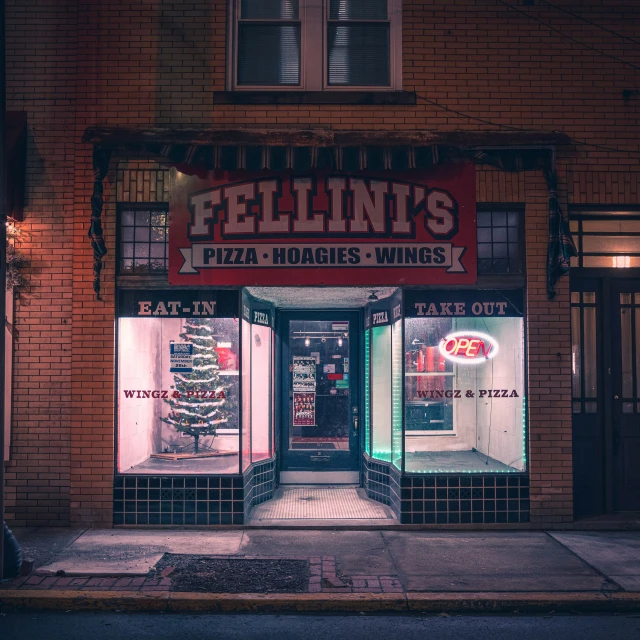 a store front of a pizzaria at night
