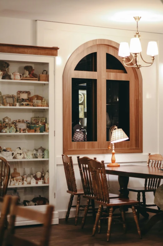 an arched window shines over a table and chairs