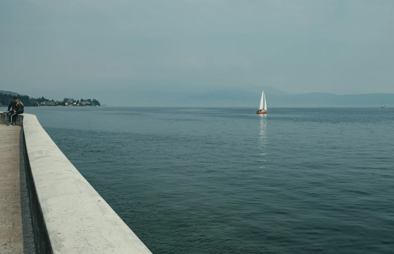 there is a sailboat in the water near a pier