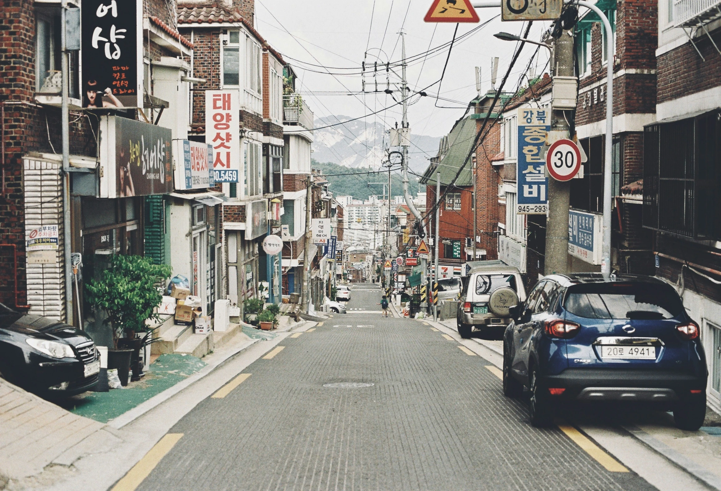 cars parked on a narrow street with buildings in the background