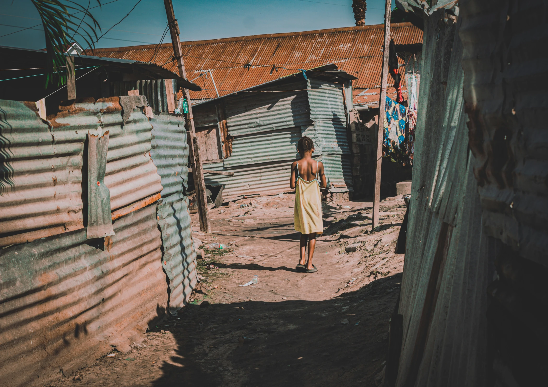 a woman walking down the street between shacks