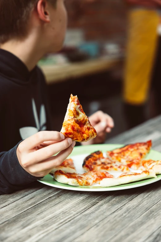 the young man is eating his pizza at the table