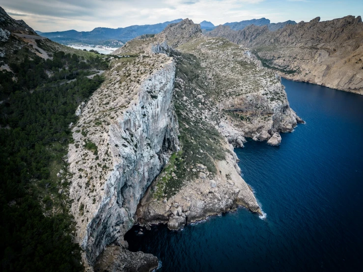 an airplane flying over some water with mountains in the background