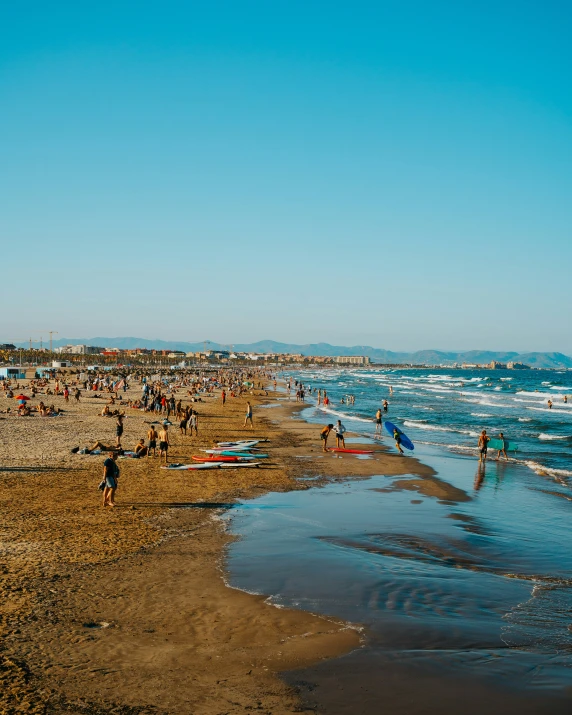 a beach with several people walking on the sand and in the water