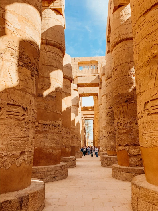 tourists stroll through the narrow corridor between two huge columns