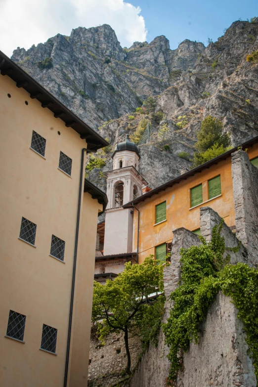 a church steeple is seen behind buildings in a mountainous area