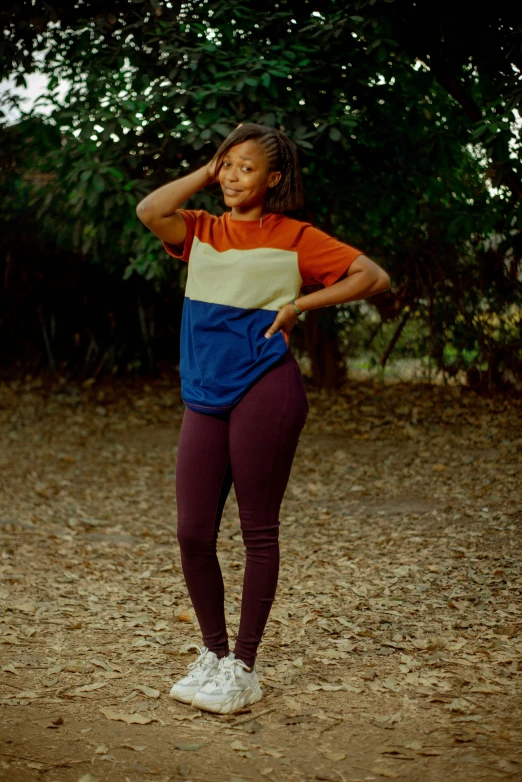 a girl wearing an orange, blue and yellow shirt holds her head