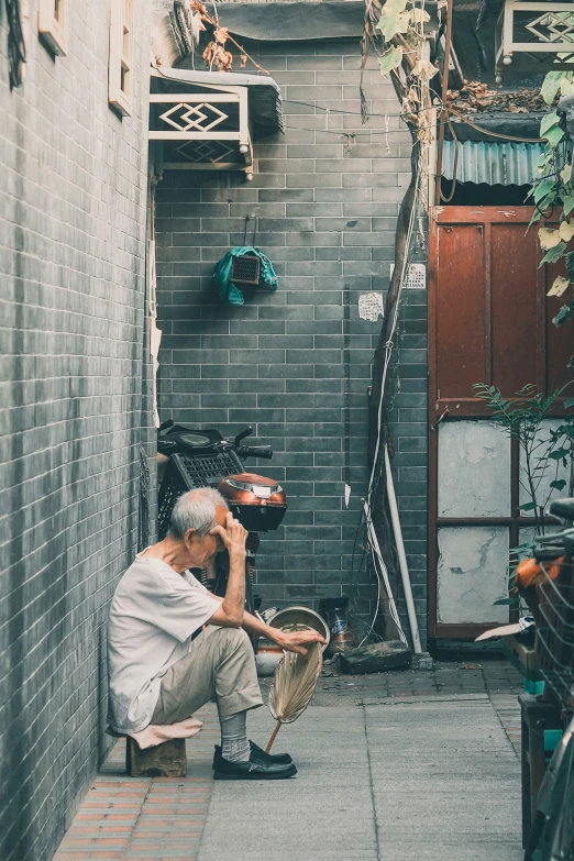 an old man sitting on the side of a building